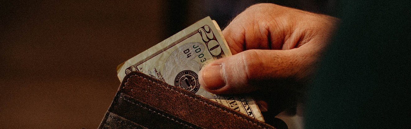 Hand taking a $20 bill out of a wallet